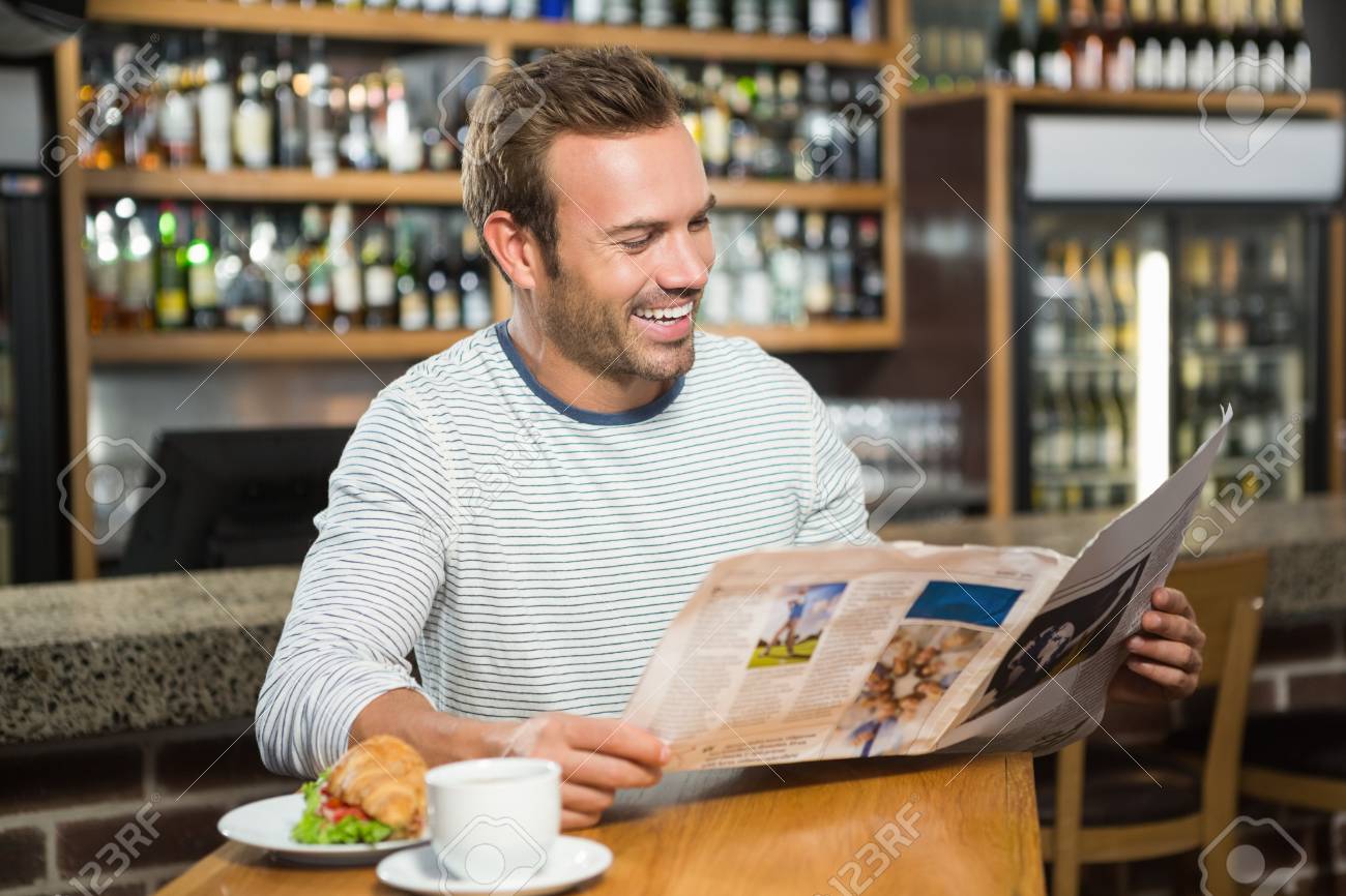Persona leyendo periódico en cafetería