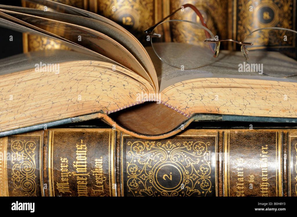 gafas de lectura apoyada en una pagina abierta de una vieja enciclopedia libros encuadernados en cuero b0h8y3